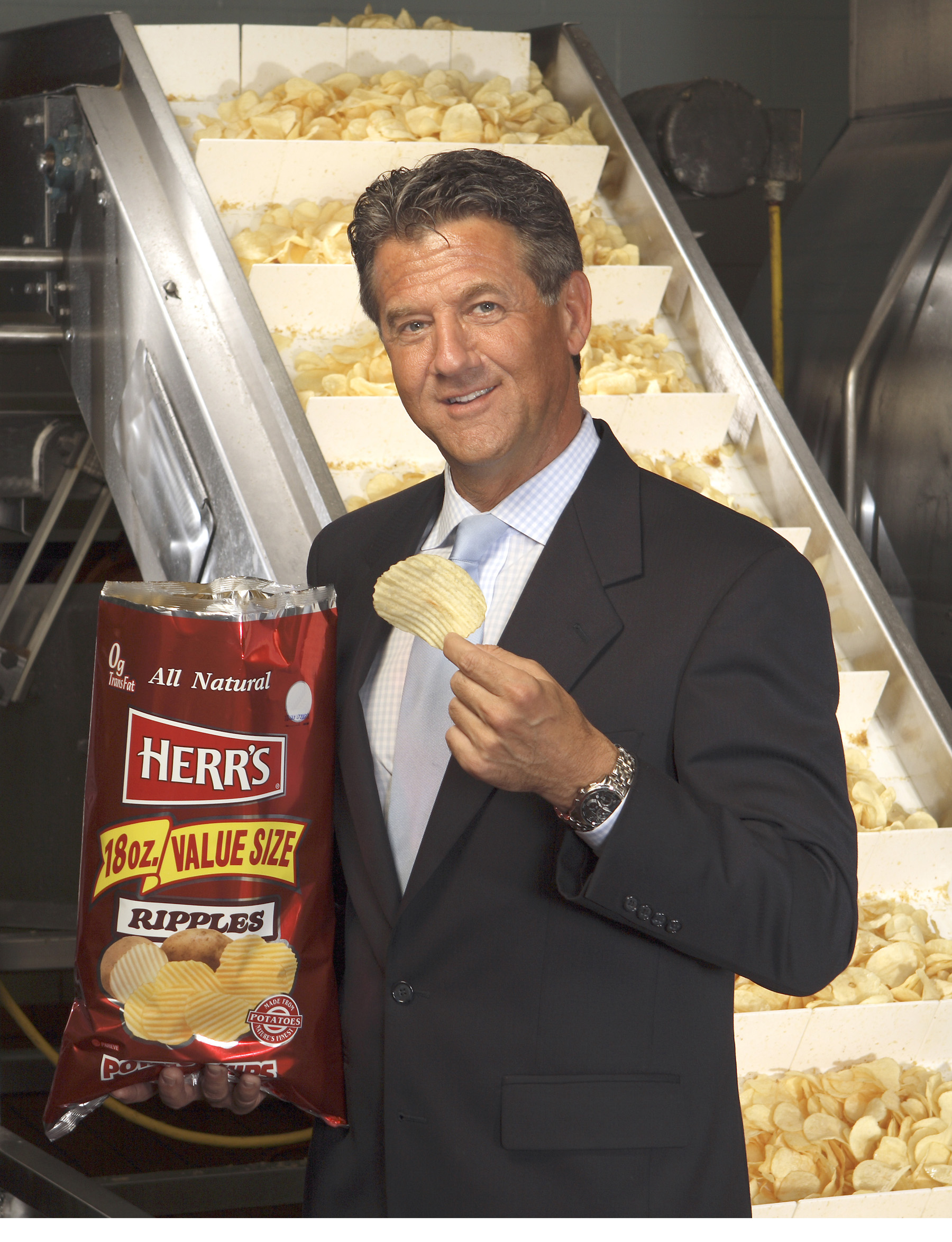 Ed Herr holding a bag of Herr's ripples potato chips in the Herr's factory