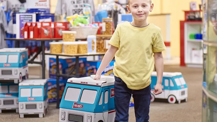 A Kid Holding A Herr's Snack Truck Box In The Herr's Gift Shop